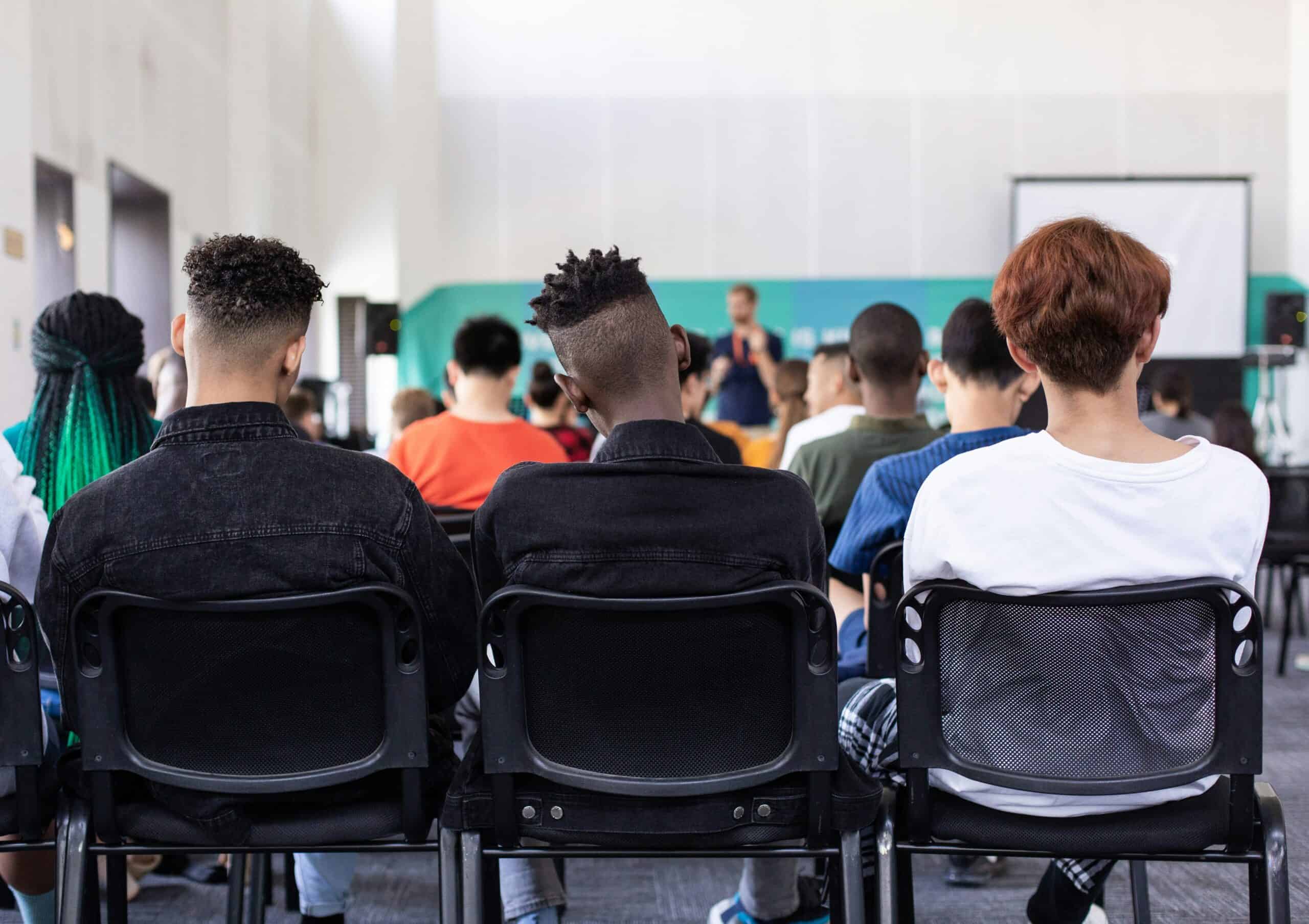 Estudantes assistindo a uma palestra ou aula em sala de aula moderna e bem iluminada, focados em intercâmbio cultural e educação internacional.